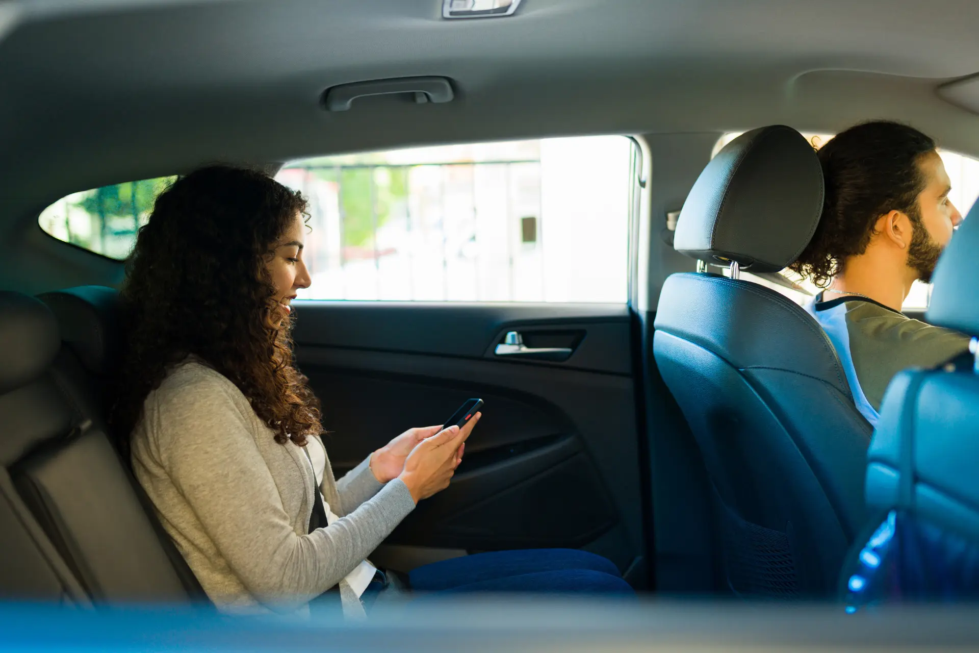 Woman using smartphone in the backseat of a car