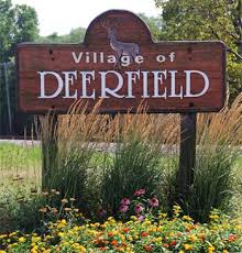 Wooden sign for the Village of Deerfield with flowers